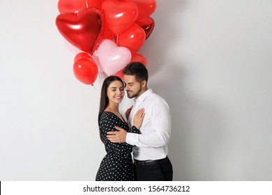 Happy young couple with heart shaped balloons on light background. Valentine's day celebration - Shutterstock ID 1564736212