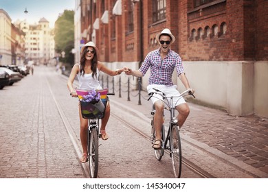 Happy young couple holding hands and riding on bike - Powered by Shutterstock