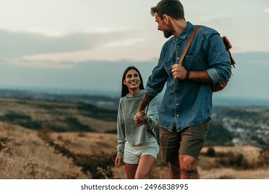 Happy young couple holding hands while walking up the hill on the summer day - Powered by Shutterstock