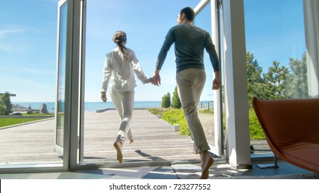 Happy Young Couple Holding Hands  Runs out of Their Home onto the Terrace with the Seaside View. - Powered by Shutterstock