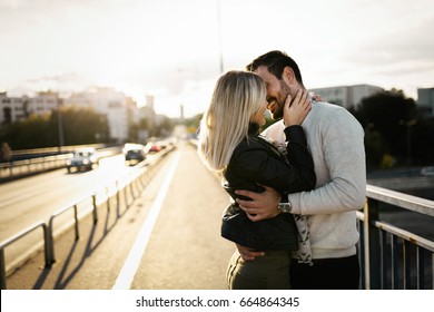 Happy Young Couple Hugging And Kissing On Bridge