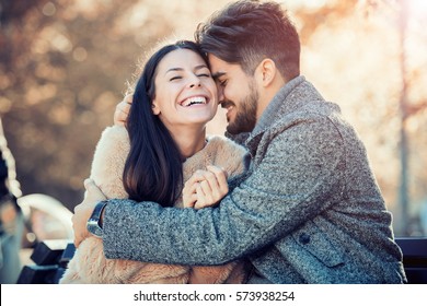 Happy young couple hugging and laughing outdoors. - Shutterstock ID 573938254