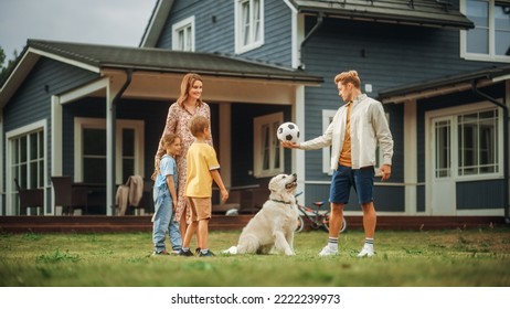 Happy Young Couple With Kids, Playing Football With A Sporty White Golden Retriever. Cheerful People Playing Ball With Pet Dog On A Lawn In Their Front Yard In Front Of The House.