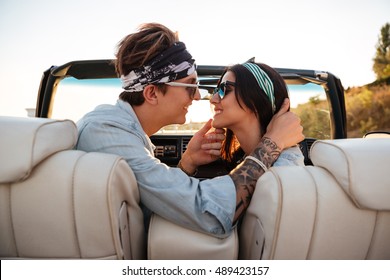 Happy young couple kissing in cabriolet in summer
