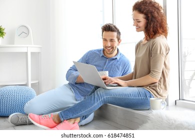 Happy young couple with laptop at home - Shutterstock ID 618474851