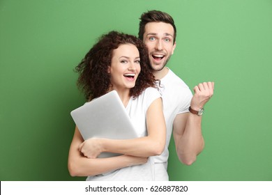 Happy Young Couple With Laptop On Color Background