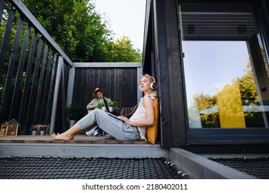 Happy Young Couple With Laptop Resting Outdoors In A Tiny House, Weekend Away And Remote Office Concept.