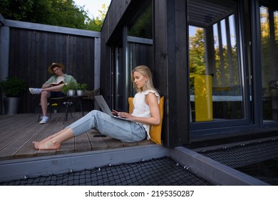 Happy Young Couple With Laptop Resting Outdoors In A Tiny House, Weekend Away And Remote Office Concept.