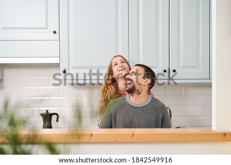 Happy young couple laughing in kitchen at home.