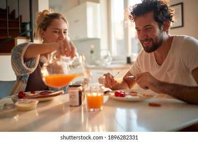 A happy young couple likes to have fresh orange juice for a breakfast on a beautiful sunny morning at home too. Relationship, love, together, breakfast - Shutterstock ID 1896282331