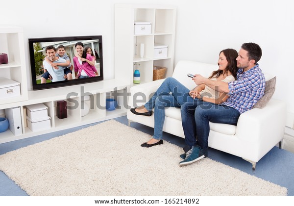 Feliz Pareja Joven En El Salón Sentada En El Sofá Viendo La Televisión