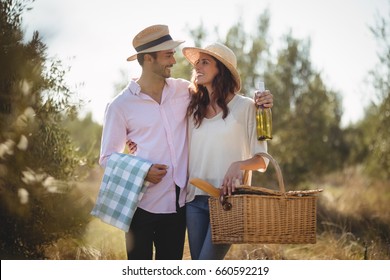 Happy young couple looking at each other while carrying picnic basket at olive farm - Powered by Shutterstock