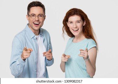 Happy young couple looking pointing fingers at camera, cheerful millennial man and woman smiling choosing advertising appealing to you as friend coaching isolated on white grey studio background