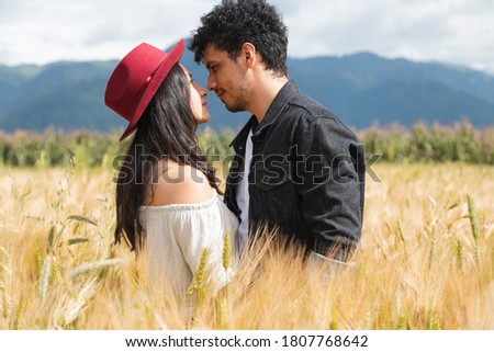 Happy young couple in love enjoying in a wheat field at sunset - Hispanic couple watching each other in the middle of the field