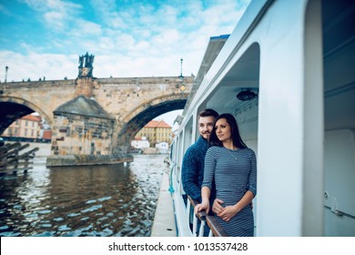 Happy young couple in love, floating on a ship near the Charles bridge at Prague