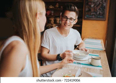 Happy Young Couple In Love Having A Nice Date In A Bar Or Restaurant. They Telling Some Stories About Themself , Drinking Tea Or Coffee And And Eating Salad And Soup