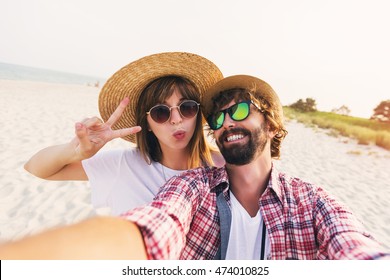 Happy young  couple in love making a selfie on phone at the beach on a sunny summer day. Pretty girl and her handsome boyfriend with beard having fun, crazy emotional faces , laughing. - Powered by Shutterstock