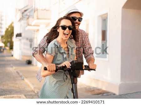 Happy young couple in love on vacation having fun, driving electric scooter through the city. Eco transport. Adventure and vacation concept