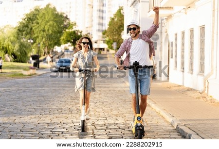 Happy young couple in love on vacation having fun, driving electric scooter through the city. Eco transport. Adventure and vacation concept