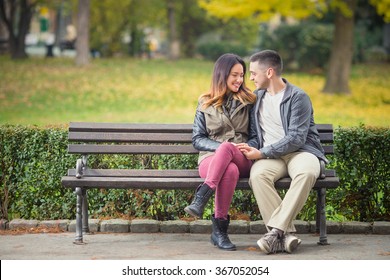 Happy Young Couple In Love Sitting On A Park Bench