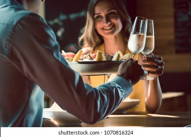 Happy young couple in love toasting with champagne during romantic dinner with seafood as oysters and crabs at the restaurant