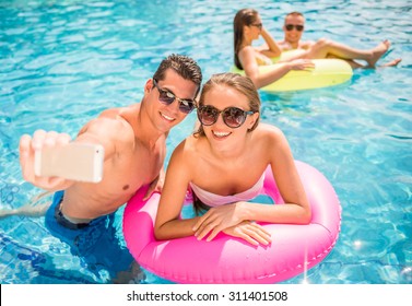 Happy Young Couple Are Making Selfie While Having Fun In Pool.