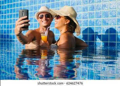 Happy Young Couple Are Making Selfie While Having Fun In Pool.