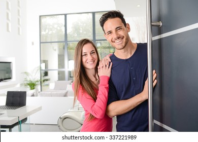 Happy Young Couple At New House Front Door Welcoming People 