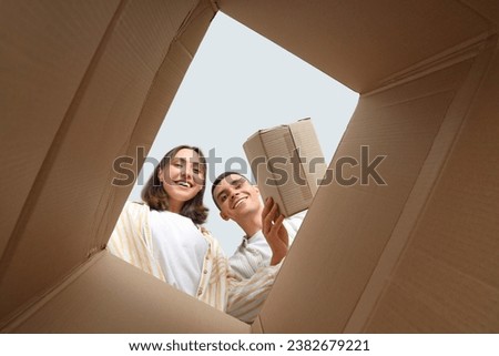 Happy young couple with open moving box, view from inside