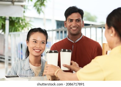 Happy young couple ordering take out coffee in coffeeshop