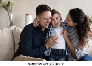 Happy young couple of parents cuddling and tickling adorable little son on couch, laughing, having fun together. Excited mom, dad, kid playing at home, feeling joy, giggling. Family time - Powered by Shutterstock