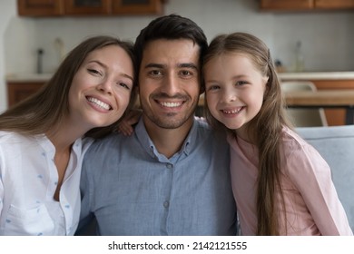 Happy young couple of parents and sweet daughter child head shot portrait. Mom, dad, kid hugging, relaxing together at home, looking at camera with toothy smiles. Parenthood concept - Shutterstock ID 2142121555