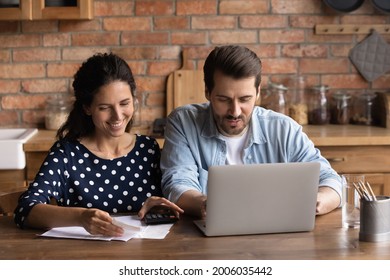 Happy Young Couple Paying Utility Bill, Taxes, Insurance, Mortgage, Loan Fees, Using Calculator And Laptop, Smiling, Discussing Expenses, Saving Money, Planning Family Budget, Calculating Concept