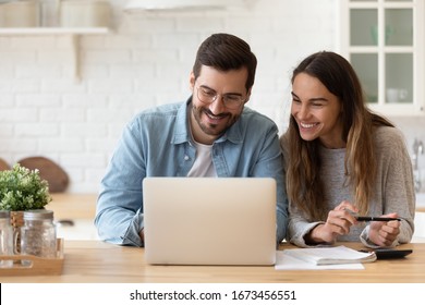 Happy Young Couple Planning Budget, Reading Good News In Email, Refund Or Mortgage Approval, Smiling Woman And Man Looking At Laptop Screen, Checking Finances, Sitting At Table At Home Together