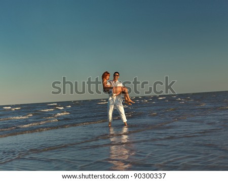 happy, young couple playing by the sea shore