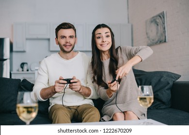 Happy Young Couple Playing Retro Video Game On Couch At Home