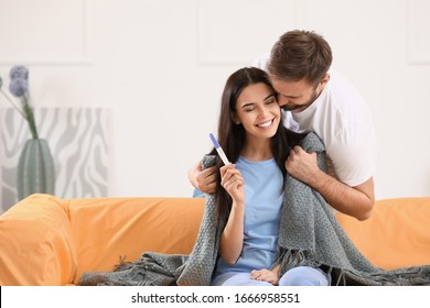 Happy Young Couple With Pregnancy Test At Home