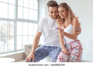 Happy Young Couple With Pregnancy Test In Bathroom