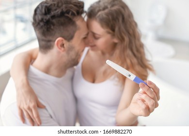 Happy Young Couple With Pregnancy Test In Bathroom