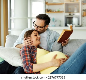 Happy young couple, pregnant woman, having fun book a reading at home - Powered by Shutterstock