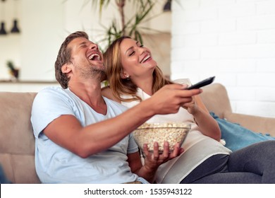 Happy Young Couple Preparing To Watch A Movie At Home.