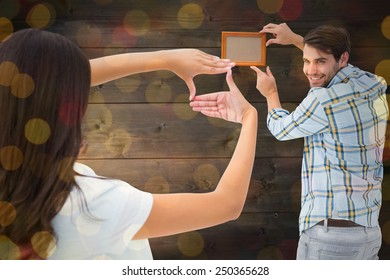 Happy Young Couple Putting Up Picture Frame Against Close Up Of Christmas Lights