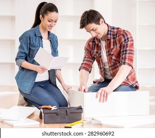 Happy young couple putting together self assembly furniture as they move into their new house. - Shutterstock ID 282960692