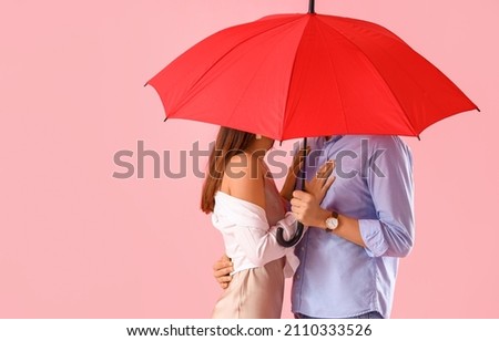 Happy young couple red umbrella on color background. Valentine's Day celebration