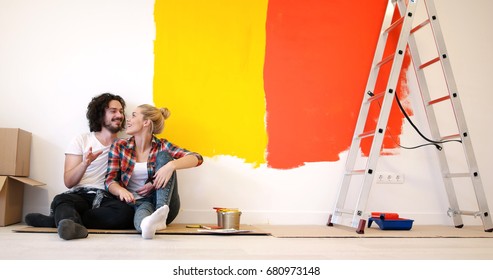 Happy Young Couple Relaxing After Painting A Room In Their New House On The Floor