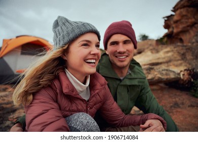 Happy Young Couple Relaxing During Camping Sitting Outside Tent Looking Away During Winter