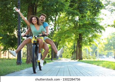 Happy young couple riding bicycle on city street