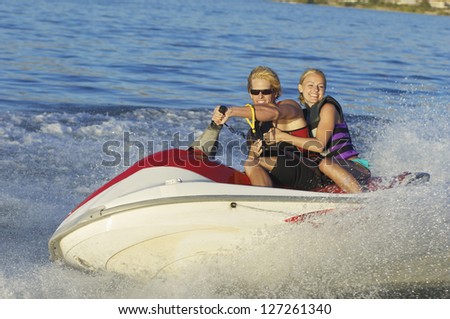 Happy young couple riding jet ski on lake