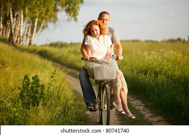 Happy Young Couple Riding On A Bicycle