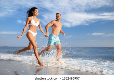 Happy Young Couple Running Together On Beach